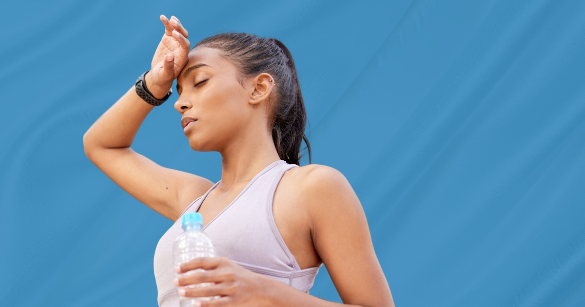 Woman pausing to cool down and rehydrate with a bottle of water, illustrating signs of heat exhaustion